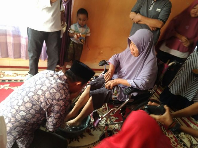 
 Foto Riduan
Caption : Cawabup Lampura Muhammad Yusrizal, saat membasuh kaki ibundanya, sebelum melakukan pencoblosan, Rabu (27/6).
 