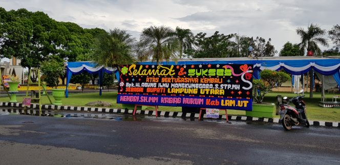 
 Foto Riduan 
Caption : Tampak salah satu karangan bunga ucapan selamat  atas bertugasnya kembali Hi. Agung Ilmu Mangkunegara sebagai Bupati Lampura telah terpasang di Halaman Pemkab Setempat. Foto dibidik sekitar pukul 13.00 WIB, Minggu(24/6).

