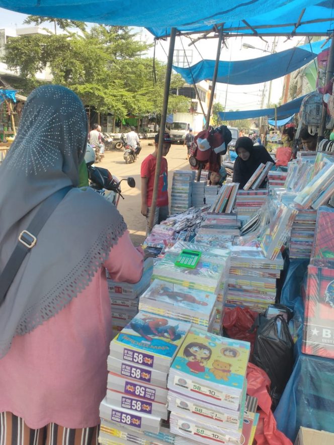 
 Foto : Ferdani
Caption :Halimah salah seorang pedagang buku dan alat tulis, saat melayani pembeli. Foto dibidik di jalan Kantor Pos Kotabumi, Minggu (1/7).  