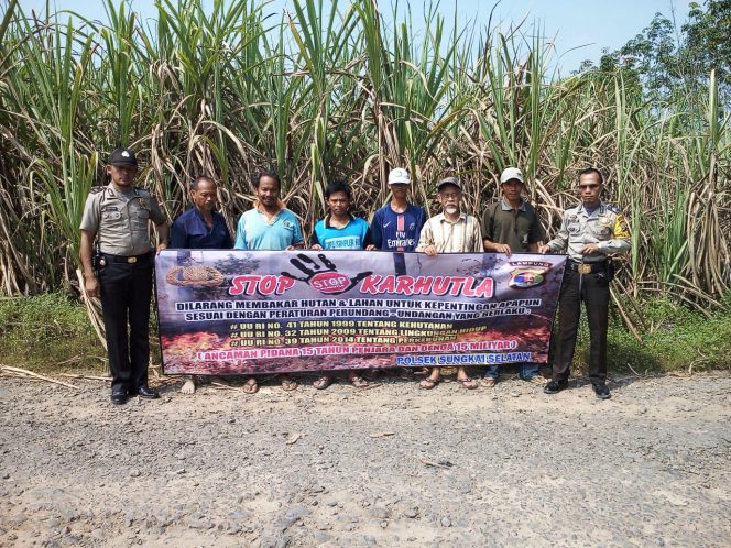 
 Foto : Humas Polres Lampura  Caption Foto : Anggota Polsek Sungkai Selatan bersama petani tebua saat membentangkan spanduk peringatan bahaya Karhutla, foto dibidik Kamis (26/7).
