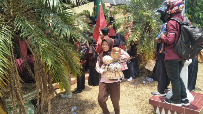 
 Caption : Salah seorang pedagang asongan nampak tengah menenteng barang dagangan saat aksi mahasiswa berlangsung. Foto dibidik di seputaran gedung DPRD Lampura, Senin (30/9). foto :  cw9  