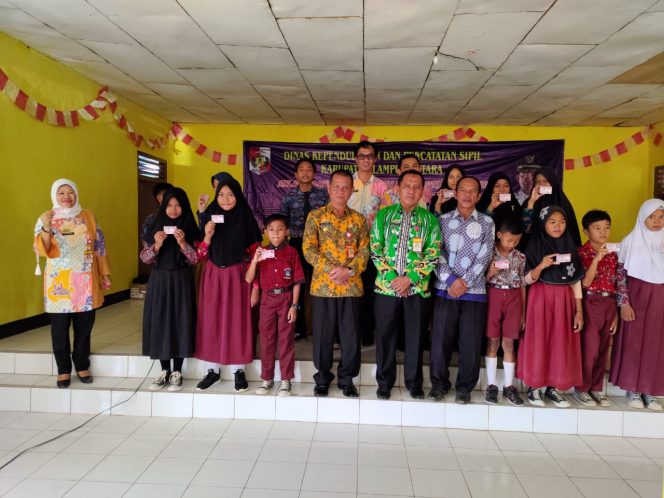 
 Caption Foto : Kadisdukcapil Lampura Maspardan saat foto bersama dengan para siswa SD dan SMP penerima KIA di Kecamatan Abung Selatan.
