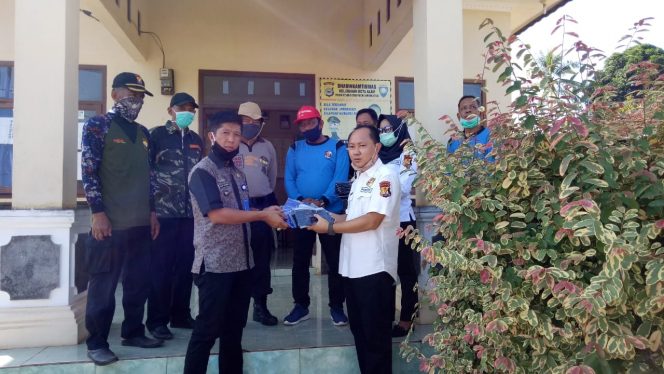 
 Foto IST :  Kepala Kesbangpol Lampura Fadly Achmad saat memberikan bantuan Masker untuk Masyarakat yang diterima langsung oleh Lurah Kota Alam, Felix Sulandana  