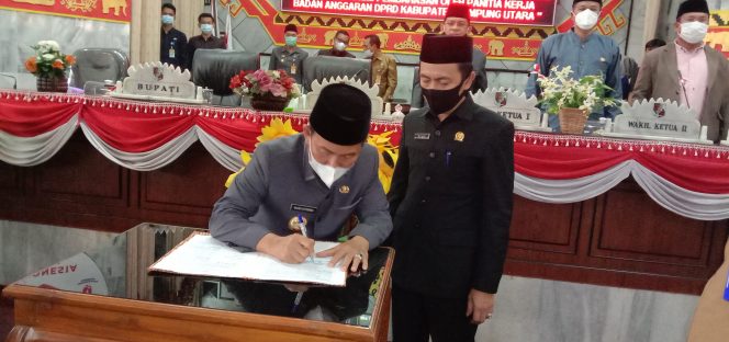 
 caption foto : Bupati Lampura Hi.Budi Utomo bersama ketua DPRD Romli menandatangani naskah rapat paripurna Pembahasan Raperda APBD 2021, Senin (16/11) 