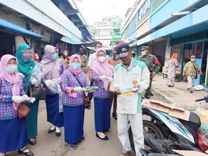 
 Foto IST  Camat Kotabumi Nujum Masya didampingi Ketua TP-PKK Kecamatan Susilawati saat membagikan Masker di Pasar Pagi.  