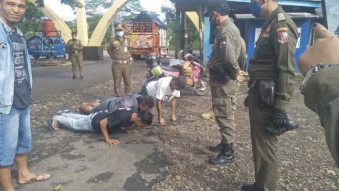 
 caption foto : Tampak Kasat Pol PP Lampura, Pirmansyah memberikan sanksi bagi pelanggar prokes dalam operasi yustisi yang digelar dipasar sentral Kotabumi, Kamis (17/12)  
