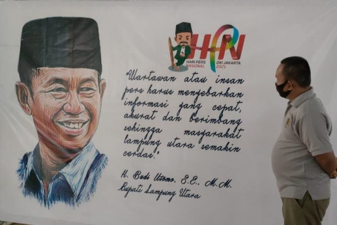 
 caption : Karikatur Budi Utomo Bupati Lampura, sebagai salah satu Kepala Daerah penerima penghargaan Tjindarboemi, yang terpasang di GOR Kotabumi, tempat Peringatan puncak  HPN secara virtual, besok (Selasa-red)
