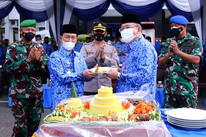 
 Foto Diskominfo Lampura  Bupati Lampura H. Budi Utomo saat menerima potongan tumpeng pertama dari Sekkab H. Lekok dalam peringatan HUT Korpri, Senin (29/11).
