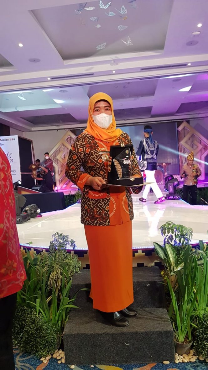 
 Foto Kepala Dinas Koperasi UMKM dan Perindustrian Lampura Dina Prawitarini saat menunjukkan Plakat Juara II Stand Terbaik se Provinsi Lampung.  