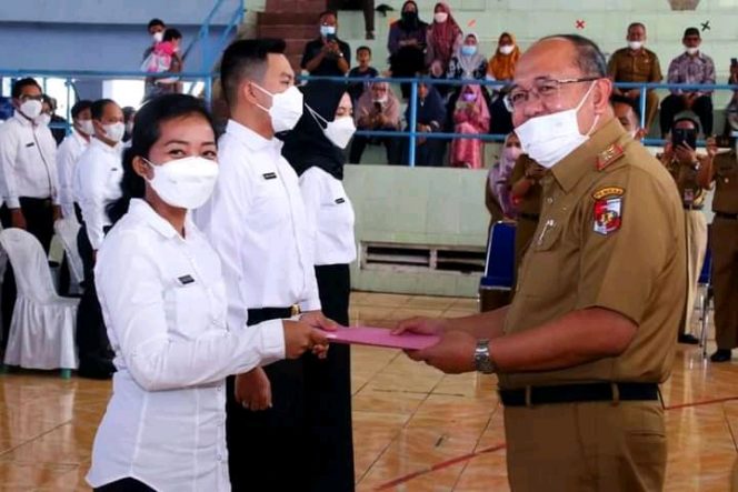 
 caption : Sekkab Lampura H. Lekok saat menyerahkan SK 80 persen kepada perwakilan CPNS di GOR Sukung Kotabumi, Selasa(12/4).
