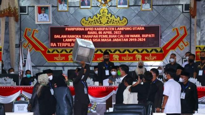 
 caption : ADV1: Proses pemungutan suara Pilwabup pada sidang paripurna DPRD Lampura. Tampak Panitia Pemilihan tengah menunjukkan kotak suara dalam keadaan kosong, sesaat sebelum pemungutan suara dilangsungkan.
