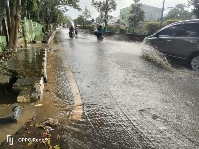 
 Salah satu titik badan Jalan Lintas Sumatra (Jalinsum), tepatnya di jalan menurun Rumah Makan Tarukojaya digenangi air hujan akibat luapan dari drainase yang tersumbat. Foto Riduan/Radar Kotabumi
