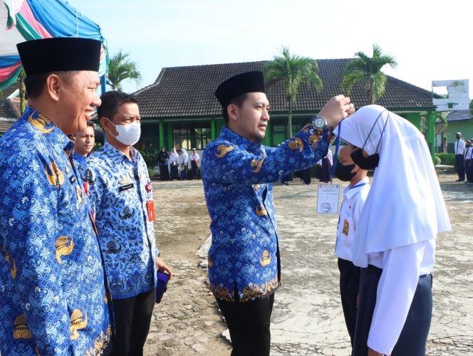 
 Foto Bagian Protokol Lampura/Ria Radar Kotabumi  Caption : Wabup Ardian Saputra, didampingi Kepala Disdikbud Lampura Hi. Mat Soleh, saat menyematkan tanda peserta didik baru dalam MPLS di SMPN 1 Abung Selatan, Senin(18/7).  