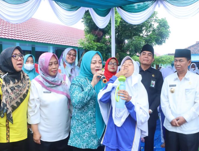 
 Bupati Lampura Hi. Budi Utomo, bersama Ketua TP-PKK Hj. Nur Endah Sulastri saat membimbing siswa dalam meminum tablet tambah darah, Rabu(26/10). Foto IST ----
