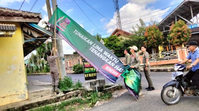 
 Tampak anggota Pol-PP Lampura menurunkan Bener/Spanduk milik Gudang Garam yang dinilai melanggar perda, Selasa 7 Maret 2023. Foto IST -----